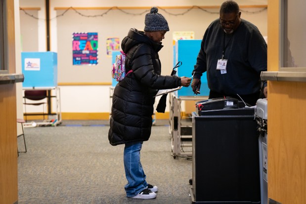 Election official Dennis Howleit helps Victoria Jackson submit her ballot during early voting in Chicago's 40th Ward at the Budlong Woods Library, 5630 N. Lincoln Ave.,March 14, 2024, in Chicago. (E. Jason Wambsgans/Chicago Tribune)