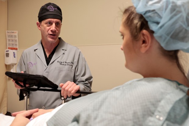 Dr. Randy Morris talks with patient Ashley Kawash before her procedure at the Naperville Fertility Center on March 20, 2024. (Antonio Perez/Chicago Tribune)