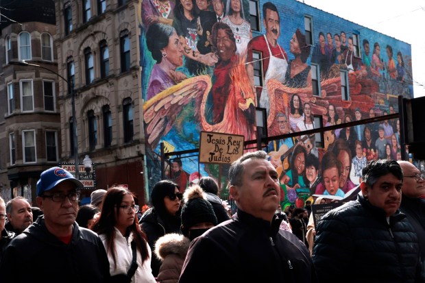 Hundreds of people walk in procession past a mural during the Good Friday Via Crucis procession in Chicago's Pilsen neighborhood on March 29, 2024. (Antonio Perez/Chicago Tribune)