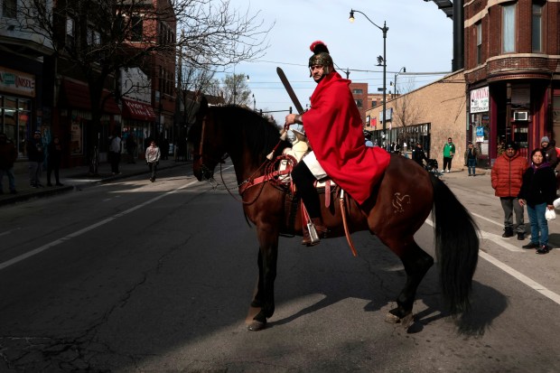 A knight on a horse looks back as hundreds of people walk during the Good Friday Via Crucis procession in Chicago's Pilsen neighborhood on March 29, 2024. (Antonio Perez/Chicago Tribune)