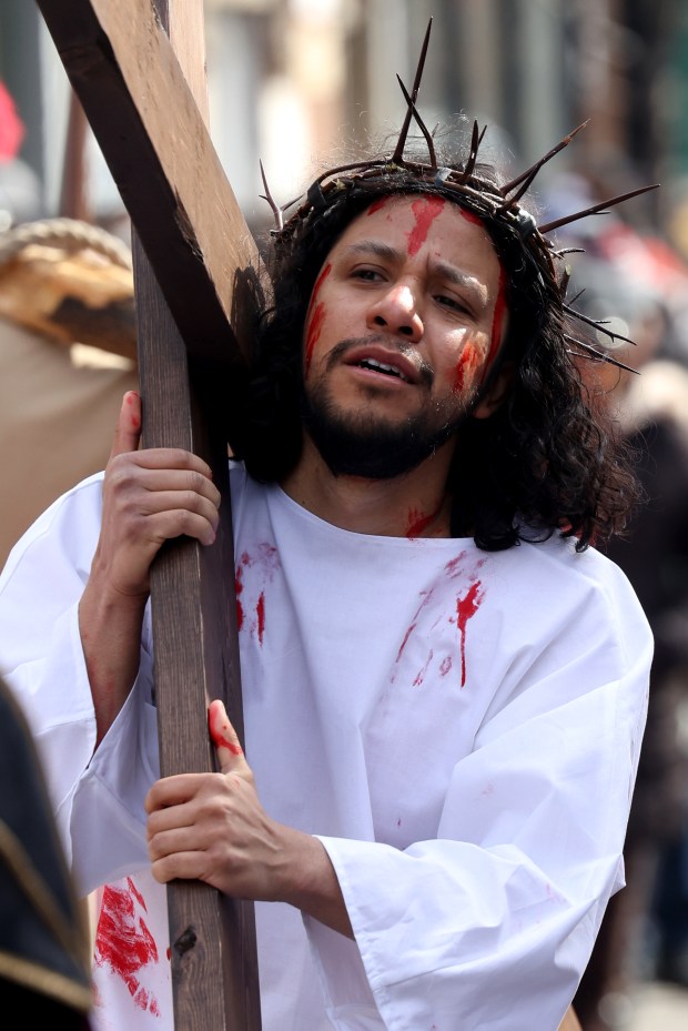 Jesus, played by Tony Diaz, carries a cross down 18th Street followed by hundreds of people in a Good Friday Via Crucis procession in Chicago's Pilsen neighborhood on March 29, 2024. (Antonio Perez/Chicago Tribune)