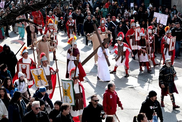 Jesus, played by Tony Diaz, carries a cross down 18th Street followed by hundreds of people in a Good Friday Via Crucis procession in Chicago's Pilsen neighborhood on March 29, 2024. (Antonio Perez/Chicago Tribune)