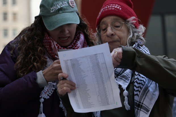 Noura Ebrahim, left, and Linda Leon check the names of people killed in Gaza as dozens of people gather at Federal Plaza in Chicago, March 7, 2024, at the start of a 24-hour vigil to remember and call out the names of the thousands of people killed in Gaza. (Antonio Perez/Chicago Tribune)