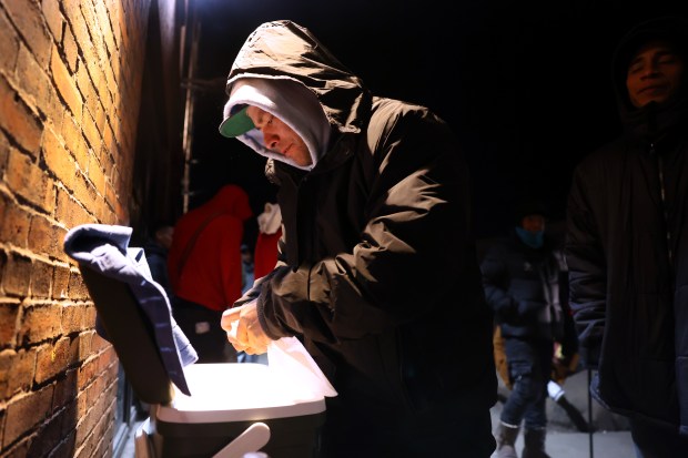 Venezuelan migrant Edwin Bravo opens his cooler while selling tequeños outside a migrant shelter on North Elston Avenue near the Salt Shed, Feb. 29, 2024. (Chris Sweda/Chicago Tribune)