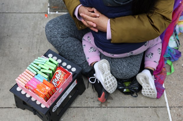 A migrant mother sells candy while holding her daughter at the corner of State and Washington streets Thursday, Feb. 22, 204, in Chicago. (John J. Kim/Chicago Tribune)