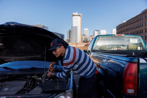 Yeiko Vaguilla, 34, from Venezuela, works on a Mazda outside a migrant shelter on North Ogden Avenue, March 10, 2024. (Armando L. Sanchez/Chicago Tribune)