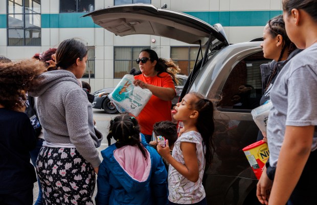 Maria Perez, center, hands out diapers, wipes and formula outside a migrant shelter on the Lower West Side on March 4, 2024, in Chicago. Migrants told the Tribune that they are not always allowed to bring in donations from outside and they're scared to talk to the media for fear of being kicked out of the shelter. (Armando L. Sanchez/Chicago Tribune)