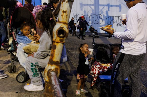 Migrants eat dinner after attending a religious service outside a shelter on the Lower West Side on Monday, March 4, 2024, in Chicago. Several religious groups organized the event to feed migrants and hold a brief service on the sidewalk outside the shelter. (Armando L. Sanchez/Chicago Tribune)