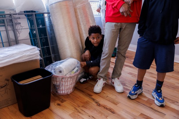 Marshall Emerick Ramirez Galvan, 7, squats next to a load of New Life Centers furniture in the family's new home in the Englewood neighborhood, Feb. 21, 2024. (Armando L. Sanchez/Chicago Tribune)