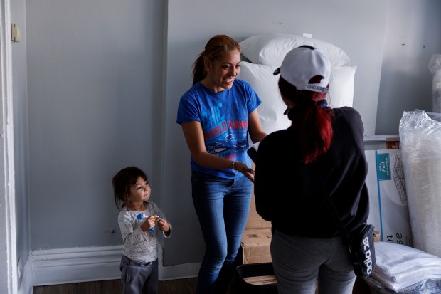 After delivering furniture, New Life Centers mover Milena Gallego, right, talks with Iris Britit and her 2-year-old child Aliss inside their home in the North Lawndale neighborhood, Feb. 21, 2024 in Chicago. (Armando L. Sanchez/Chicago Tribune)