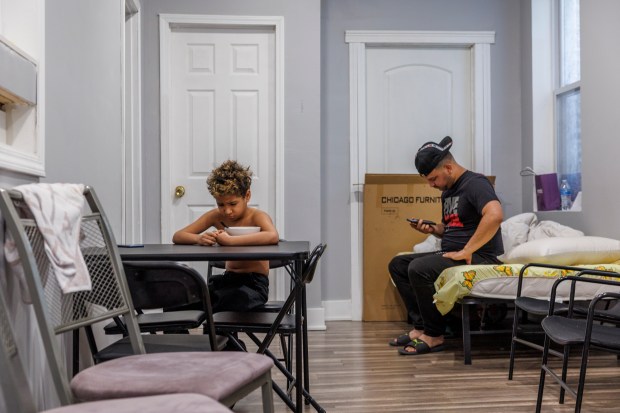 Engerberth Morales, 8, cries over his breakfast while his relative, Angel Pírela, sits on his bed in the kitchen on Feb. 22, 2024. (Armando L. Sanchez/Chicago Tribune)