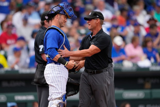 Umpire Jim Wolf greets Chicago Cubs catcher Yan Gomes prior to a spring training baseball game against the Los Angeles Angels, Wednesday, March 6, 2024, in Mesa, Ariz. (AP Photo/Matt York)