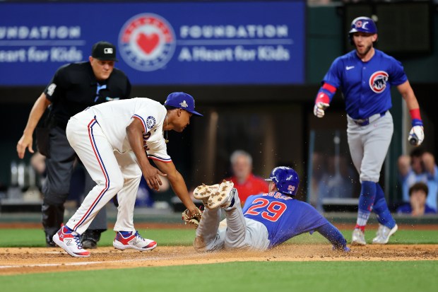 ARLINGTON, TEXAS - MARCH 28: Michael Busch #29 of the Chicago Cubs beats a tag by Jose Leclerc #25 of the Texas Rangers to score a run during the ninth inning of the Opening Day game at Globe Life Field on March 28, 2024 in Arlington, Texas. (Photo by Stacy Revere/Getty Images)