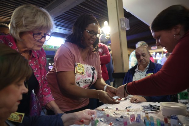 Kelli Simmons, center, of Morgan Park, browses for shoes to decorate during a meeting of the Windy City Collectors, Chicago's longest running collectors club for Barbie collectors, at Russell's Barbecue in Elmwood Park on Nov. 9, 2023. (Trent Sprague/Chicago Tribune)