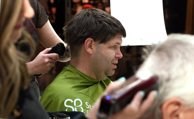 Center, shavee Steve Kitzman of Gurnee is having a buzz haircut for a cause by Hawthorn Mall's Tricoci Salon & Spa Stylist Marisa Sneider of Round Lake Park on March 23, 2024 at Rock the Bald with Hawthorn at Hawthorn Mall in Vernon Hills. (Karie Angell Luc/Lake County News-Sun)