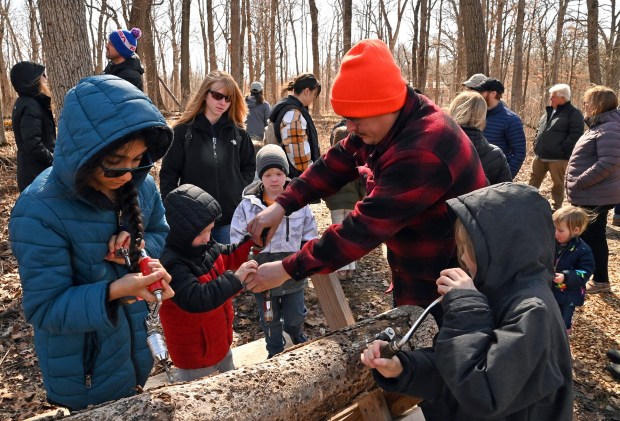 Center, Mason Schaller, 4, of Lake Zurich is being helped by his father Tim, in orange hat, in drilling a sample hole at Ryerson Conservation Area in Riverwoods on March 9, 2024 (Karie Angell Luc/Lake County News-Sun)