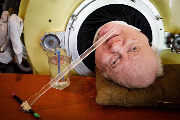 FILE - In this Friday, April 27, 2018 photo, attorney Paul Alexander looks out from inside his iron lung at his home in Dallas. Alexander died Monday, March 11, 2024 at a Dallas hospital, said Daniel Spinks, a longtime friend. He said Alexander had recently been hospitalized after being diagnosed with COVID-19 but did not know the cause of death. (Smiley N. Pool/The Dallas Morning News)