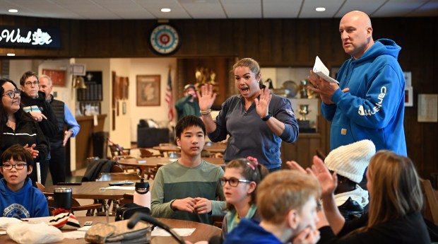 Lis Collins of Evanston, youth event coordinator, waves at students to welcome them. Collins grew up in Northbrook and is a 2003 Glenbrook North High School graduate. On right in blue sweatshirt is Matt Walz, adapted physical education teacher, at the Chicago Curling Club on March 1, 2024 in Northbrook (555 Dundee Road). (Karie Angell Luc/Pioneer Press)