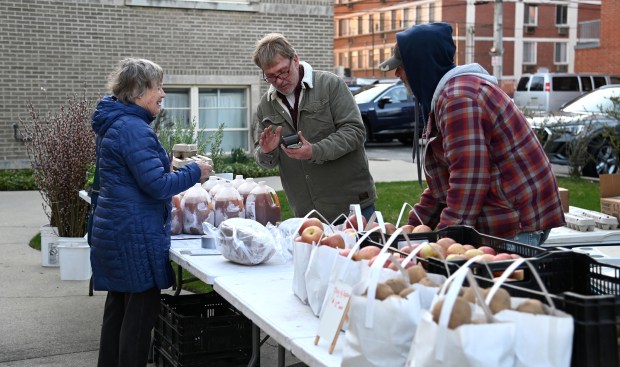 From left to right, Vikki Proctor of Evanston, a shopper, makes a purchase from Ed Gast and his brother Jason Gast of Eau Claire, Michigan and of Gast Farm, also of Eau Claire, Michigan at Evanston's Community Winter Indoor Farmers' Market at Immanuel Lutheran Church in Evanston (616 Lake St.) in Evanston on March 16, 2023. (Karie Angell Luc/for the Pioneer Press)