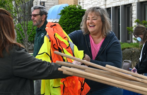 Outside of the Civic Building, right, Ellen Westel of Northbrook, then Northbrook Civic Foundation president, (with Ed Samson of Northbrook in the background upper left) hands out vests to Alisa Martorano of Norwood Park, director of development of TotalLink2 Community of Northbrook. Taken at the Northbrook Civic Foundation's Clean Up Northbrook on May 15, 2021 in Northbrook.