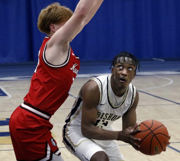 Bishop Noll's Caleb Parks (right) eyes the basket as Munster's Blake Trilli ties to block him during a basketball game on Wednesday, November 22, 2023 (John Smierciak / Post Tribune)