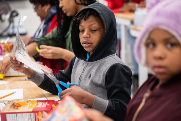 Gary Resident Kion Glover Jr., 9, cuts a piece of tin foil as he and others create a device to view the upcoming partial solar eclipse during a program at the Gary Public Library on Saturday, March 23, 2024. (Kyle Telechan/for the Post-Tribune)