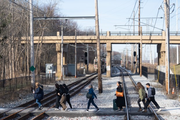 Passengers cross the double tracks on a pedestrian crossing at Dunes Park Station after disembarking from a westbound South Shore train on Tuesday, March 19, 2024. (Kyle Telechan/for the Post-Tribune)