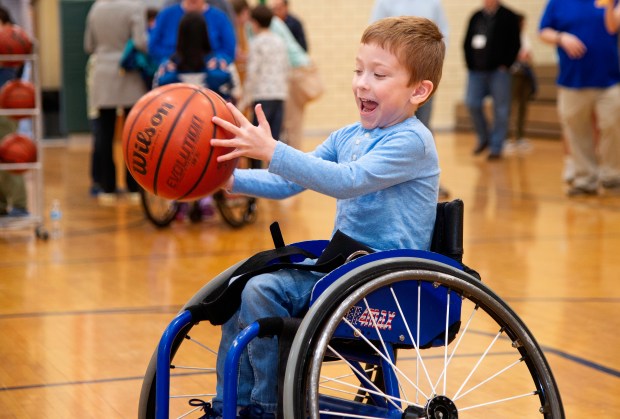 Six-year-old Charlie Smith of Chesterton catches a basketball while in a wheelchair modified for the sport during an author reading and wheelchair basketball demonstration on Saturday, March 16, 2024 at Thomas Jefferson Middle School in Valparaiso. (Michael Gard/for the Post-Tribune)