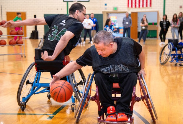 Jorge Alfaro of the Chicago Skyhawks wheelchair basketball team, right, demonstrates the sport with teammate Ramon Medina during an author reading and wheelchair basketball demonstration on Saturday, March 16, 2024 at Thomas Jefferson Middle School in Valparaiso. (Michael Gard/for the Post-Tribune)