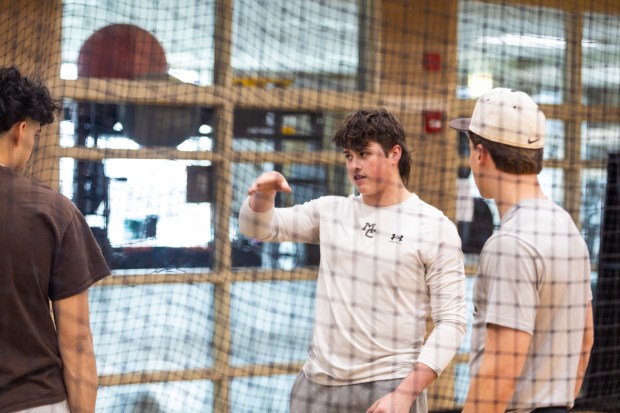 Mount Carmel's T.J. McQuillan talks with teammates during indoor-batting practice in Chicago on Saturday, March 23, 2024. (Vincent D. Johnson/for the Daily Southtown)