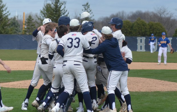 Lemont's Max Michalak (2) gets mobbed by his teammates after his single scored the winning run against Sandburg during a nonconference game in Lemont on Saturday, March 16, 2024. (Jeff Vorva / Daily Southtown)