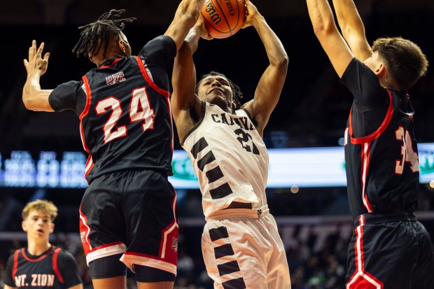 Mount Carmel's Cameron Thomas (21) goes to the basket as Mt. Zion's Brayden Trimble (24) attempts to block during the Class 3A state semifinals at the State Farm Center in Champaign Friday, March 8, 2024. (Vincent D. Johnson/for the Daily Southtown)