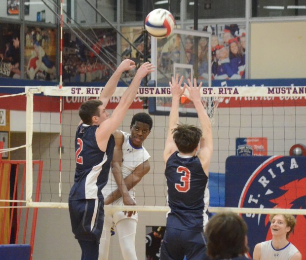 Sandburg's Jeremiah Aro, middle, hits through a block against St. Rita during a nonconference match in Chicago on Tuesday, March 26, 2024. (Jeff Vorva / Daily Southtown)