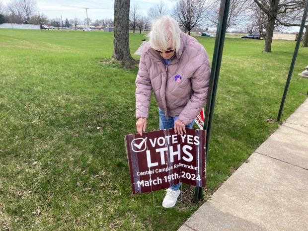 Audrey Manly puts out a sign in support of the Lockport High School District 205 referendum outside the Lockport Police Department polling place Tuesday. (Alexandra Kukulka/Daily Southtown)