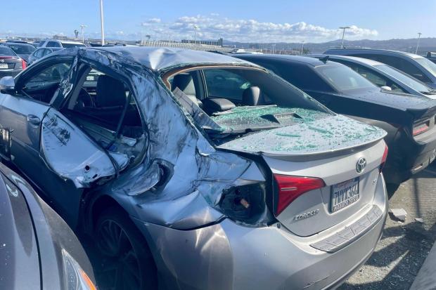 A damaged car is seen in an on-airport employee parking lot after tire debris from a Boeing 777 landed on it at San Francisco International Airport, Thursday, March 7, 2024. A United Airlines jetliner bound for Japan made a safe landing in Los Angeles on Thursday after losing a tire while taking off from San Francisco. (Haven Daley/AP)