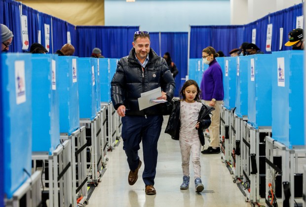 After voting, Lawrence Weisler and his 6-year-old child James Weisler walks past voting booths at the Chicago Board of Elections' Loop Super Site the day before Illinois' primary Election Day on March 18, 2024.(Armando L. Sanchez/Chicago Tribune)