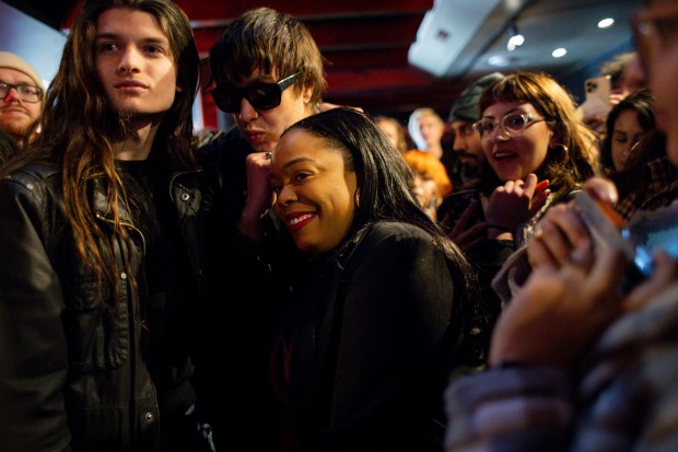 Julian Casablancas, in sunglasses, the lead singer of The Strokes, takes a photograph with a fan, left, and Kina Collins, center, 7th Congressional District candidate, during a campaign event for Collins on March 9, 2024, at the Cobra Lounge in Chicago. Casablancas and The Strokes played a concert supporting Collins' campaign the night before. (Vincent Alban/Chicago Tribune)