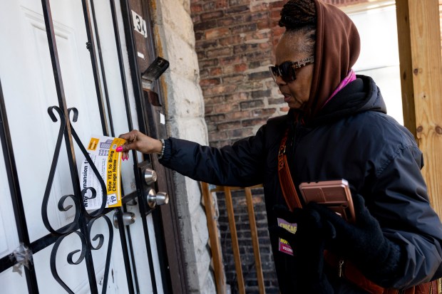 Carla Johnson, a formerly homeless volunteer with the Chicago Coalition for the Homeless, leaves a flyer at the door of a resident of the North Lawndale neighborhood while canvassing on Saturday, Feb. 17, 2024. (Vincent Alban/Chicago Tribune)