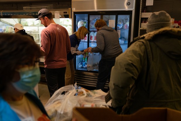 Volunteers handle food items at Nourishing Hope-Sheridan Market on Monday, Feb. 26, 2024. Food pantries in Chicago are struggling to meet demand with the influx of migrants in the city. (E. Jason Wambsgans/Chicago Tribune)