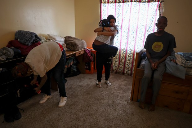 Jakayla Kelly lifts up her sister, Ke'Asia Kelly, in a hug as their mother, Kiana Kelly, left, looks for something in a drawer and their brother Hezekiah sits on a bed in the family's apartment in Highland Park on Wednesday, Jan. 3, 2024. (Eileen T. Meslar/Chicago Tribune)