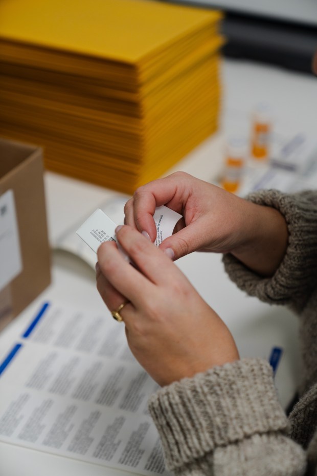 A social and reproductive health consultant with Aid Access, an organization that mails abortion pills around the country, affixes labels onto bottles of the medical abortion pill mifepristone while preparing packages to be sent to patients in states where abortion is illegal, on Oct. 19, 2023. (Sophie Park/The New York Times)