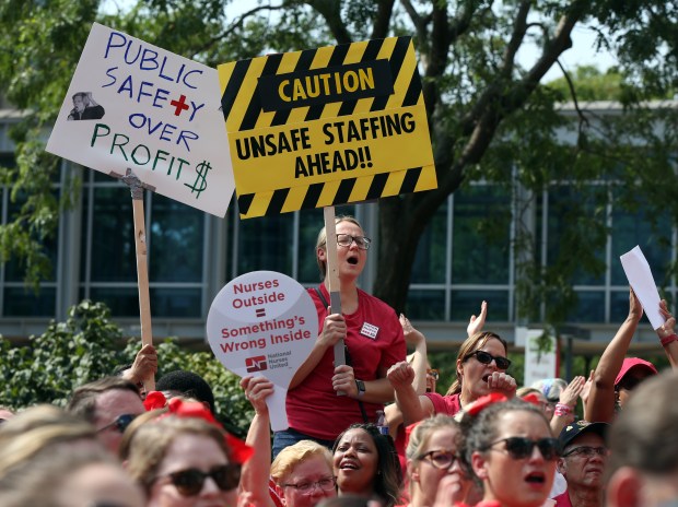 Katelyn Know, holding "caution" sign, expresses her support for nurses at the University of Chicago Medical Center as they rally outside the Duchossois Center for Advanced Medicine during a one-day strike on Sept. 20, 2019. (Terrence Antonio James/Chicago Tribune)