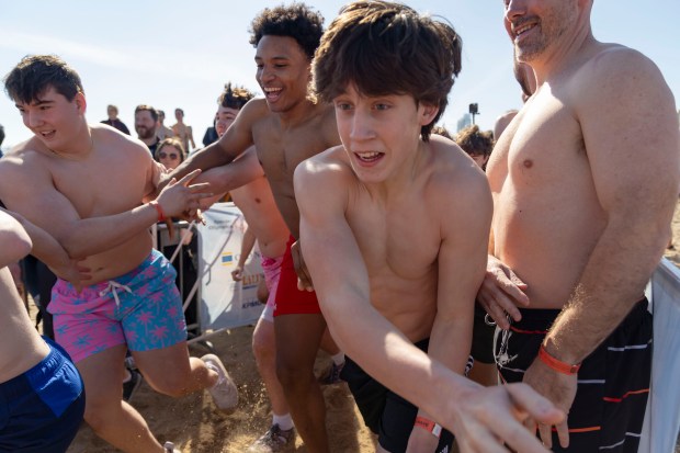 Participants charge down the beach to take a dip in Lake Michigan on a warm morning during the 24th Annual Chicago Polar Plunge, Sunday, March 3, 2024, at North Avenue Beach. (Brian Cassella/Chicago Tribune)