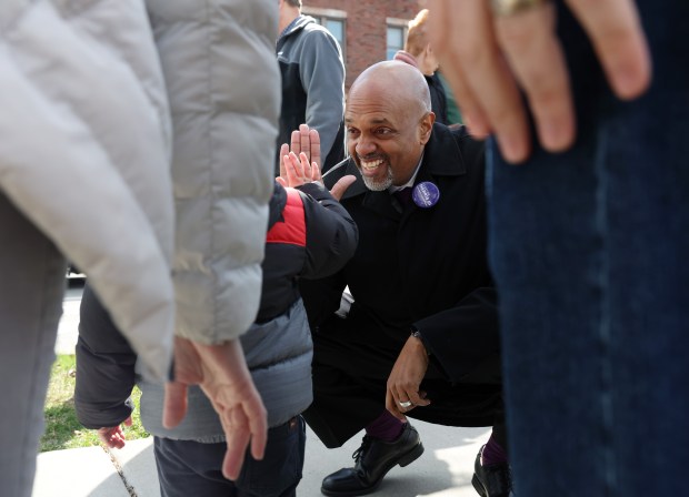 Clayton Harris III, Cook County state's attorney candidate, gives a high-five to a toddler whose parents had finished voting moments earlier, outside an early voting polling place in the Chicago Public Library Northtown Branch, 6800 N. Western Ave. on Saturday, March 16, 2024, in Chicago. (John J. Kim/Chicago Tribune)