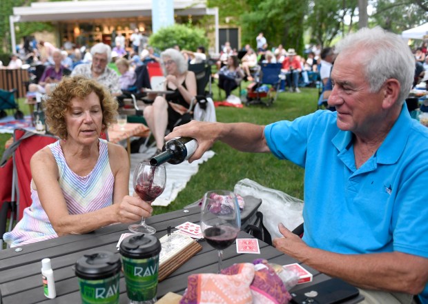 Maureen and Bob Carson pour wine while picnicking on the lawn before opening night of the 87th Chicago Symphony Orchestra Residency at the Ravinia Festival in Highland Park on July 14, 2023. (Michael Schmidt/For Pioneer Press)