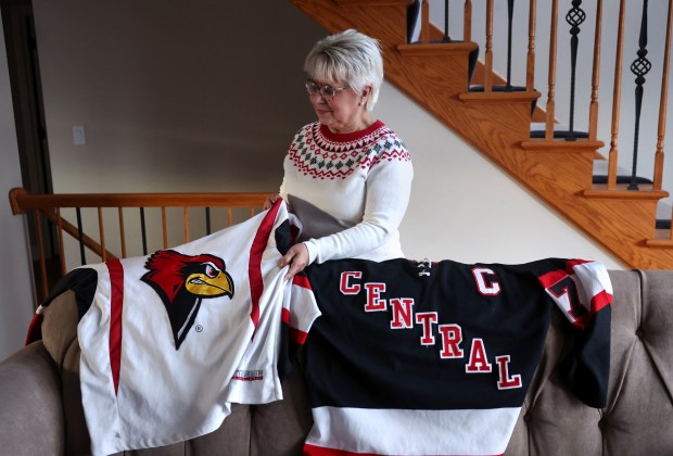 Suzy Flack shows off the hockey sweaters her son Drew wore from his time on the Naperville Central High School team and on a club team at Illinois State University, Feb. 16, 2024. (Chris Sweda/Chicago Tribune)