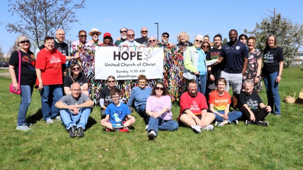 Members from the congregations of HOPE United Church of Christ and Bethany United Methodist Church, along with officials from the city of Aurora, pose in front of the sign for HOPE United Church of Christ. The sign is now adorned with ribbons in LGBTQ+ pride flag colors after the church's pride flag was recently vandalized. (R. Christian Smith / The Beacon-News)