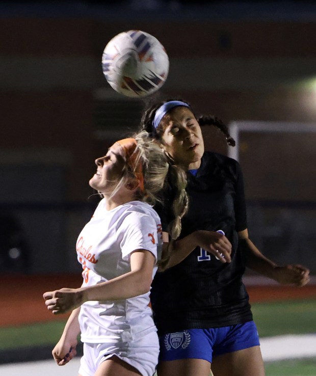 St. Charles East's Payton Rivard and St. Charles North's Juliana Park go up for the ball during the soccer game Tuesday, April 23, 2024, in St. Charles. (James C. Svehla/for the Beacon News)