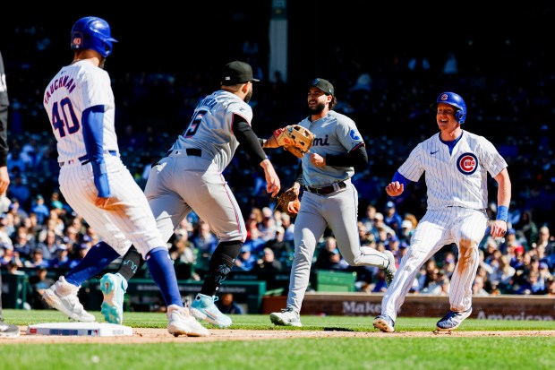 Cubs first baseman Garrett Cooper, far right, smiles while running back to third base before getting tagged out by Marlins third baseman Emmanuel Rivera (15) on April 19, 2024, at Wrigley Field. (Vincent Alban/Chicago Tribune)