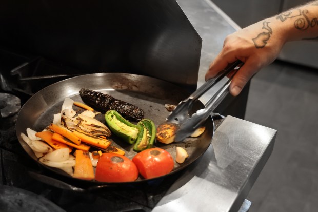 Chef Norman Fenton browns vegetables for salsa de molcajete on April 9, 2024. The restaurant makes sure to use up perfectly good bits of food like onions, carrots, peppers and limes that might otherwise end up in the trash. (Terrence Antonio James/Chicago Tribune)